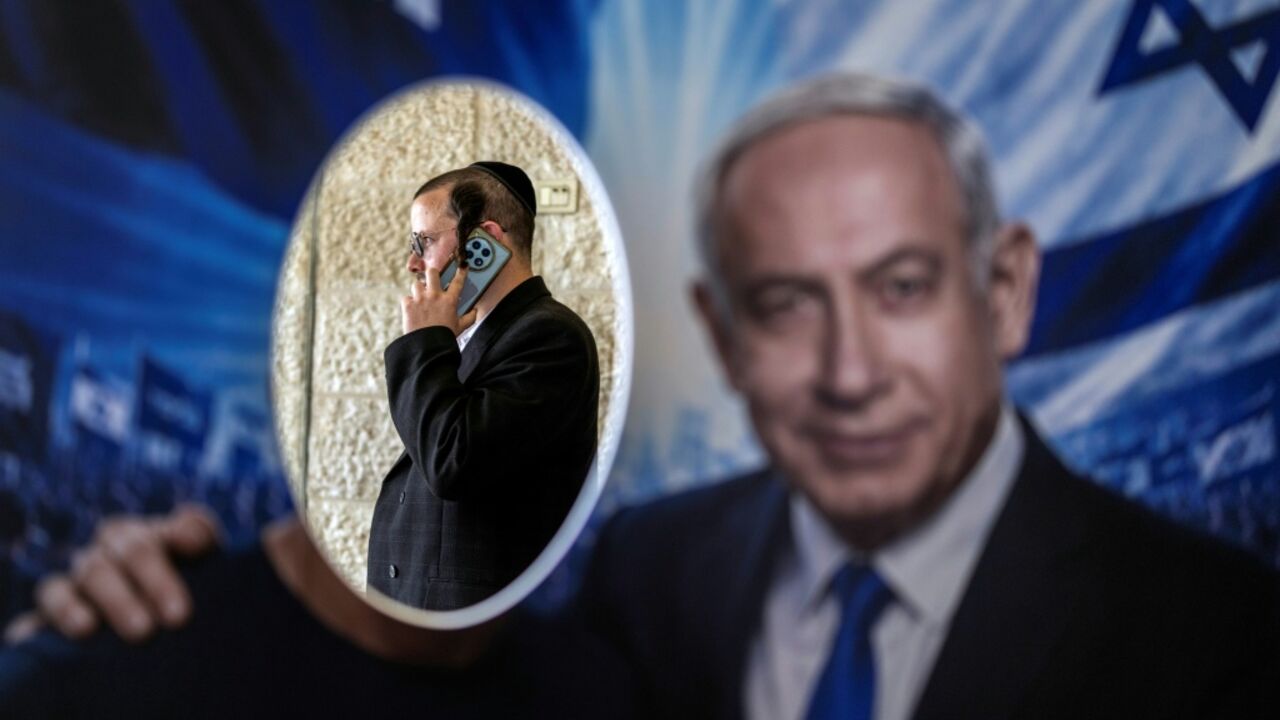 A member of Likud party is pictured through a poster with an image of Israeli Prime Minister Benjamin Netanyahu at a polling statoin during primary elections on August 17, 2026 in Jerusalem