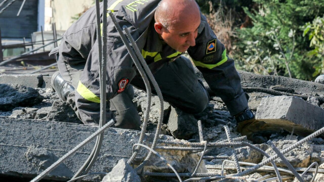 A rescuer searches for survivors in the rubble following an airstrike on the village of Kfar Rumman in Lebanon