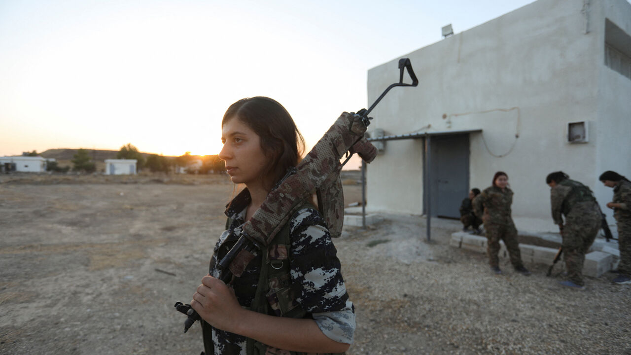 A female fighter from the Women's Protection Units (YPJ) walks with her weapon slung over her shoulder in Hasakah, Syria, August 22, 2026. REUTERS/Orhan Qereman