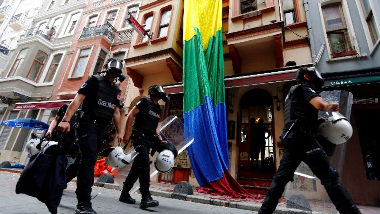 FILE PHOTO: Riot police, with a rainbow flag in the background, chase LGBT rights activists as they try to gather for a pride parade, which was banned by the governorship, in Istanbul
