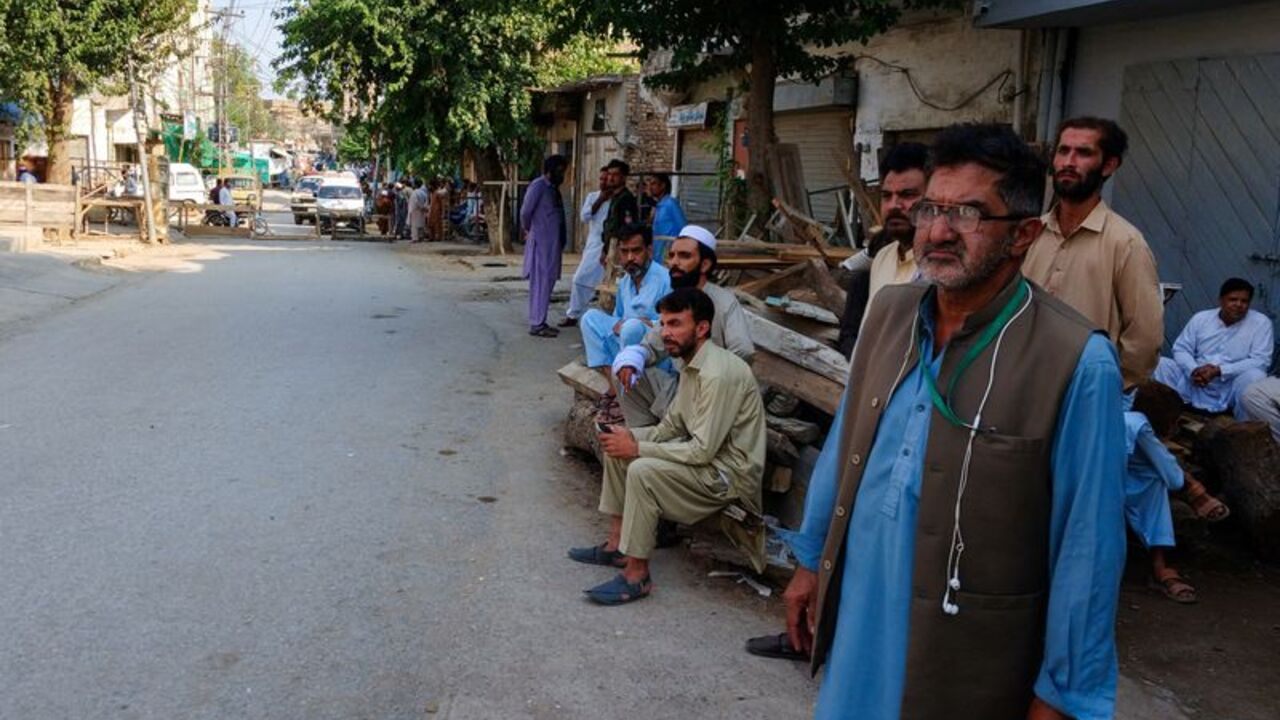 Residents gather on a street leading to a police facility, where ambulances are parked following a suicide attack in Kohat