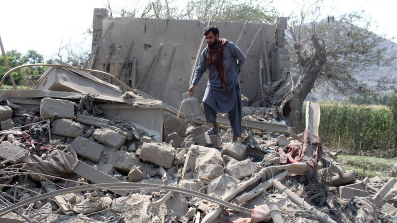 A man retrieves belongings from the debris of a house that was damaged in what the Taliban said was a Pakistani airstrike in Kunar province