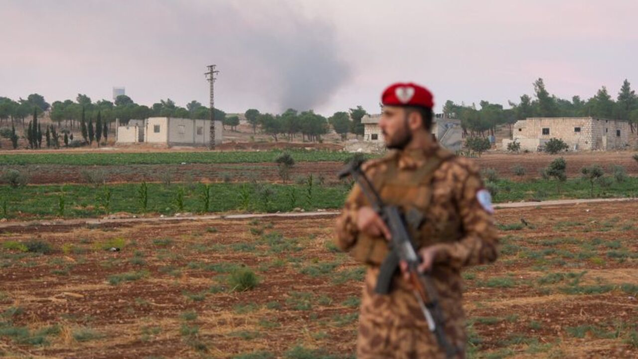 Military police officer stands on a road following an explosion at a weapons depot
