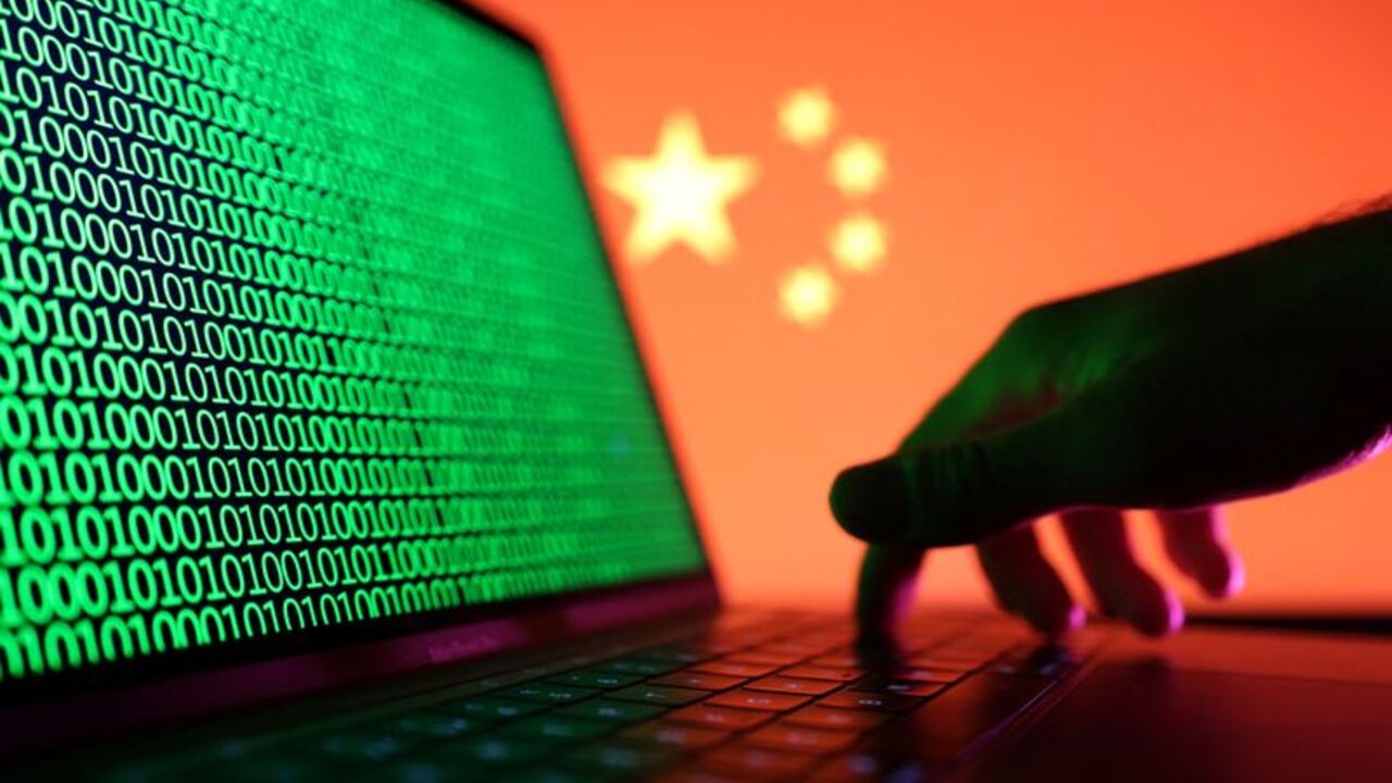 FILE PHOTO: A hand is seen on a laptop with binary codes displayed in front of the Chinese flag