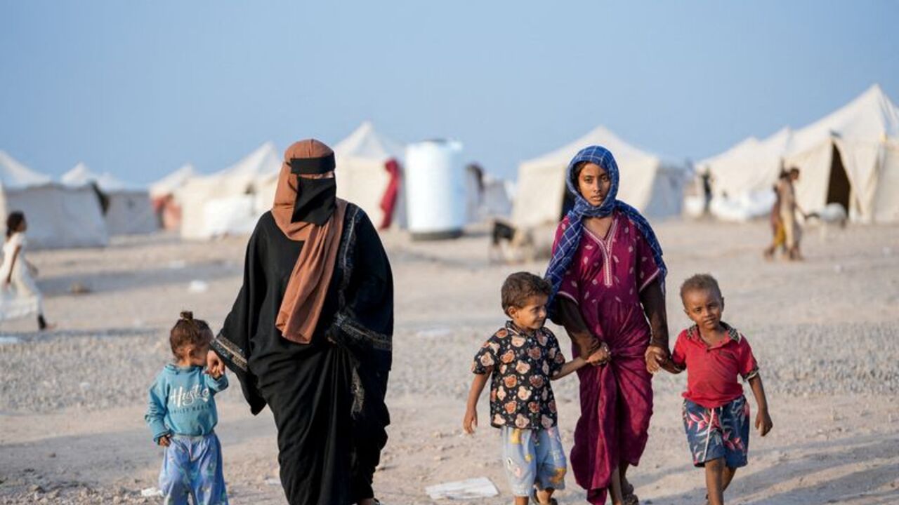FILE PHOTO: Women and children walk at camp for internally displaced people near Aden