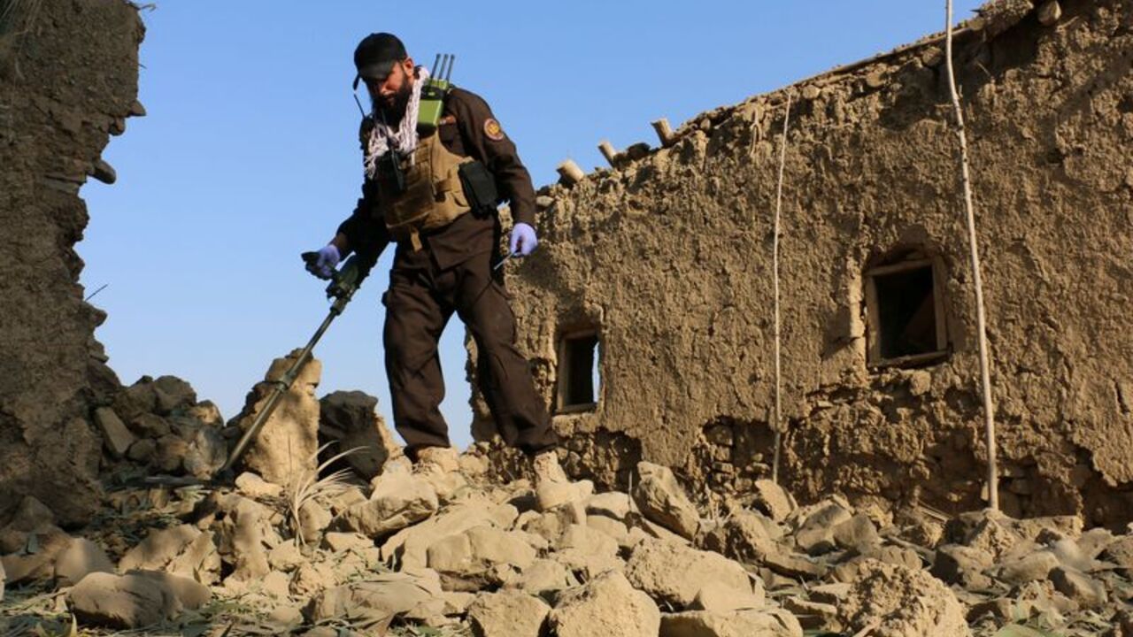 A member of Taliban security forces uses a metal detector amid the rubble of a house that was damaged in what the Taliban said was a Pakistani airstrike in Gurbuz
