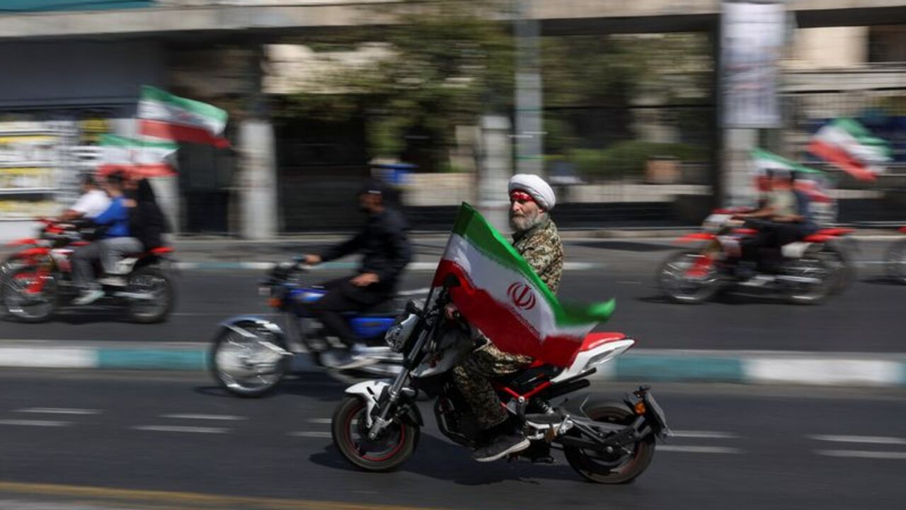 An Iranian cleric rides on a motorcycle as he participates in a march in Tehran