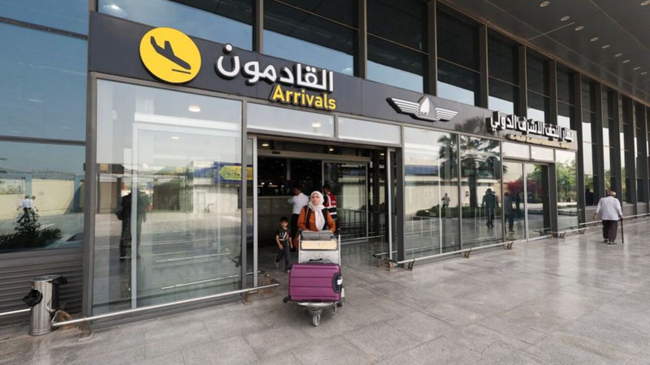 An Iranian passenger carrying luggage leaves Najaf International Airport after arriving on an AVA