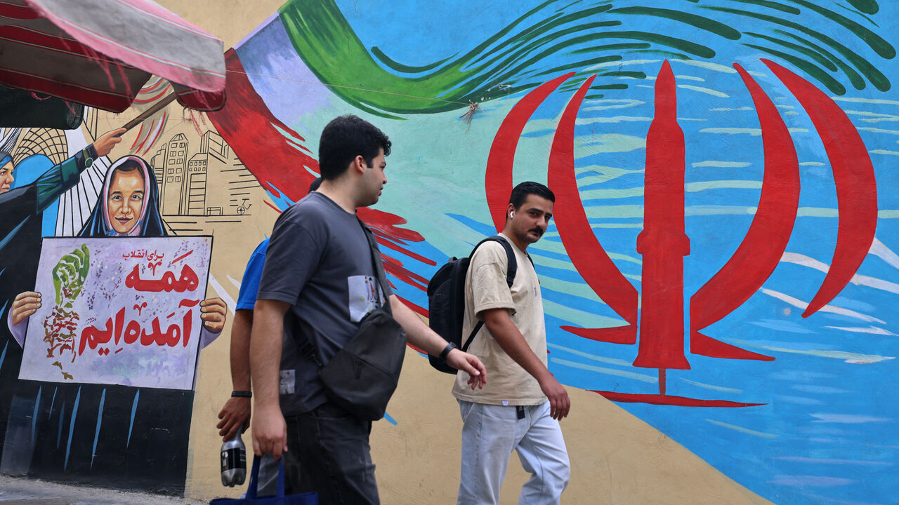 Pedestrians walk past a wall mural along a street in downtown of Tehran on Aug. 31, 2026.
