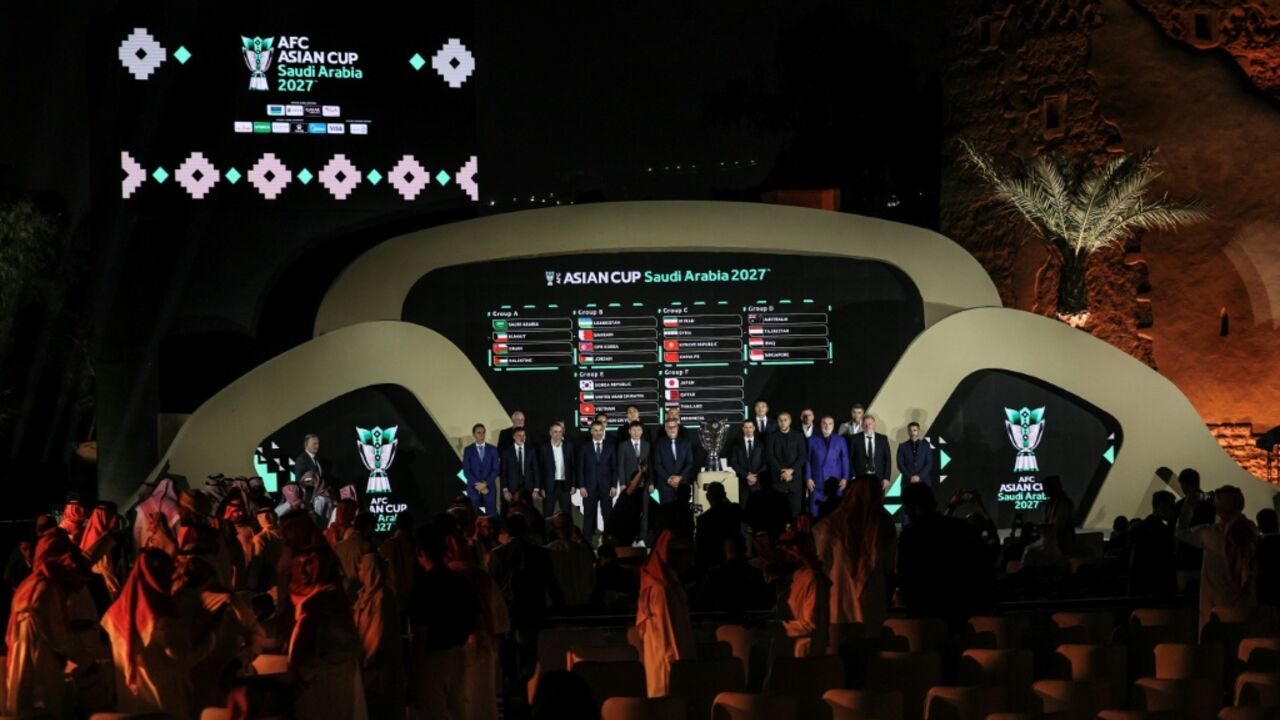 Coaches of Asian national football teams pose in front of a screen showing the results of the draw last year