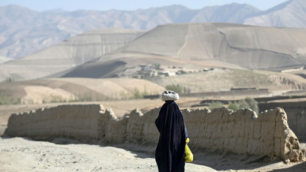 An Afghan burqa-clad woman walking along a road in the Argo district of Afghanistan's Badakhshan province