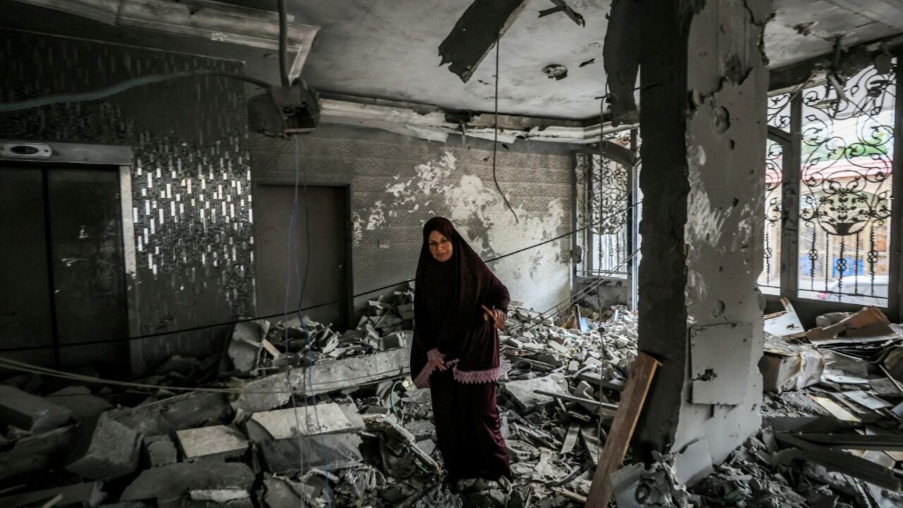 A woman inspects debris in a heavily damaged apartment building following an Israeli strike in Gaza City that Israel said targeted the top Hamas leader in the territory