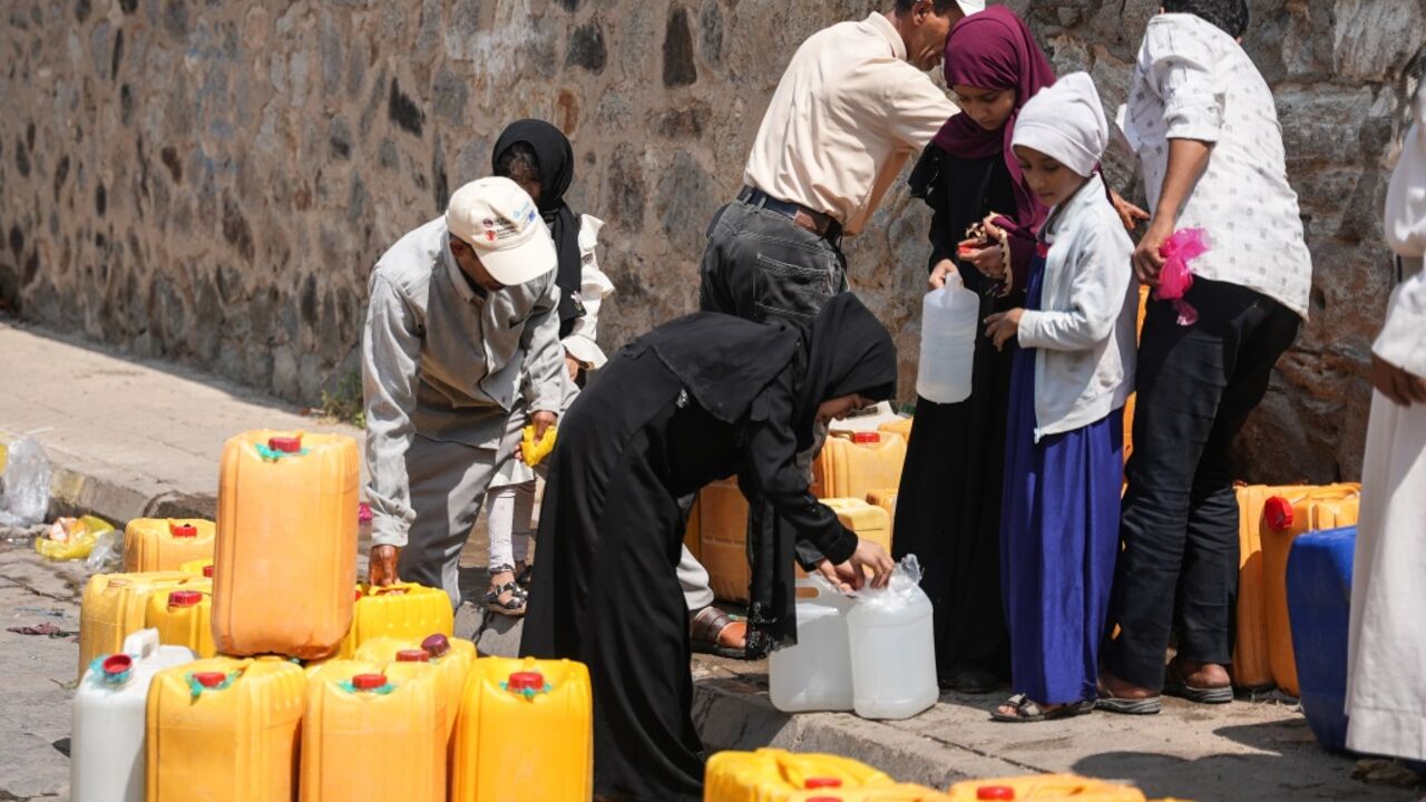 Yemenis filling jerrycans with water at a distribution point in encircled Taiz
