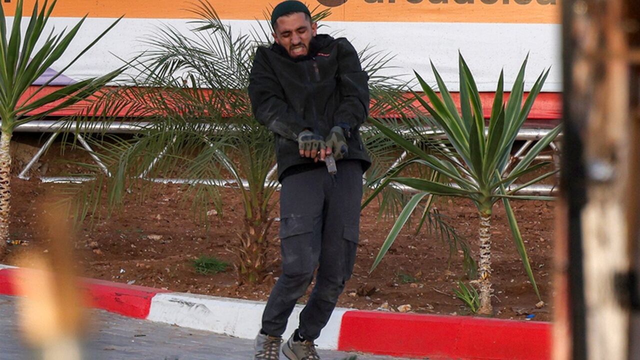 One of two armed Palestinian men loads his firearm during a fire exchange with Israeli forces at the northern checkpoint of Hebron in the Israeli-occupied West Bank on