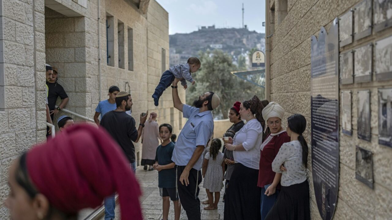 Israeli settlers wait outside a polling station in the occupied West Bank city of Hebron