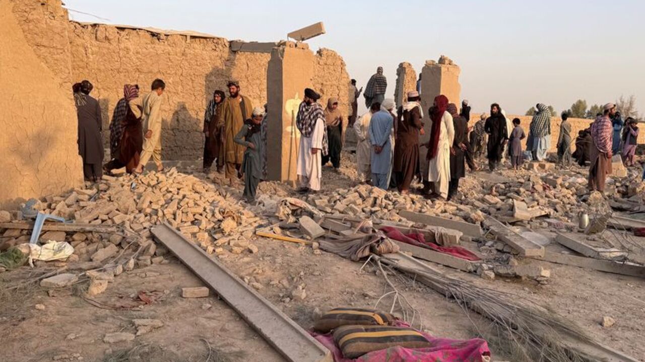 People stand on the rubble of a house that was damaged in what the Taliban said was a Pakistani airstrike in Garmsir
