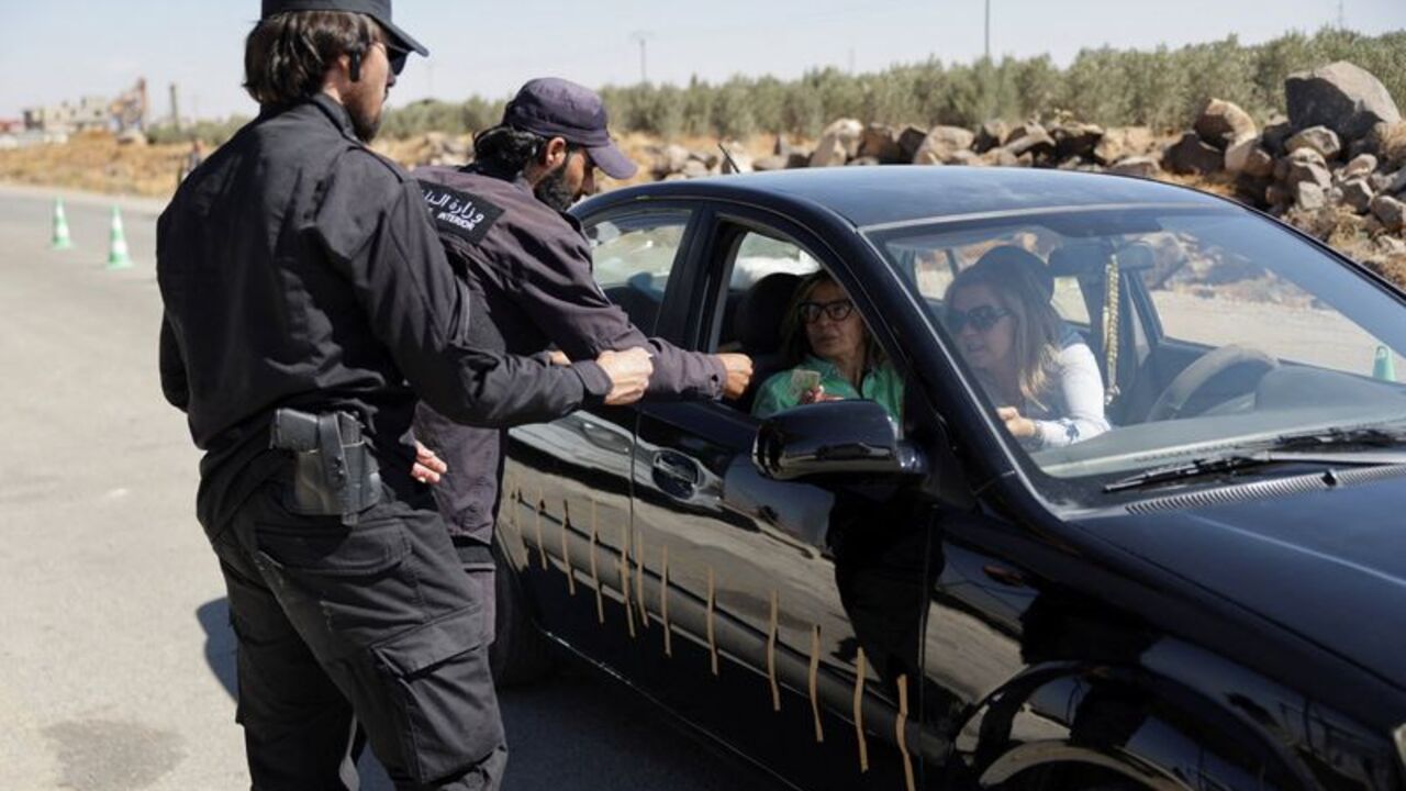 Two members of the security forces check the identification documents of people in a vehicle at a checkpoint on the outskirts of Sawara Sughra