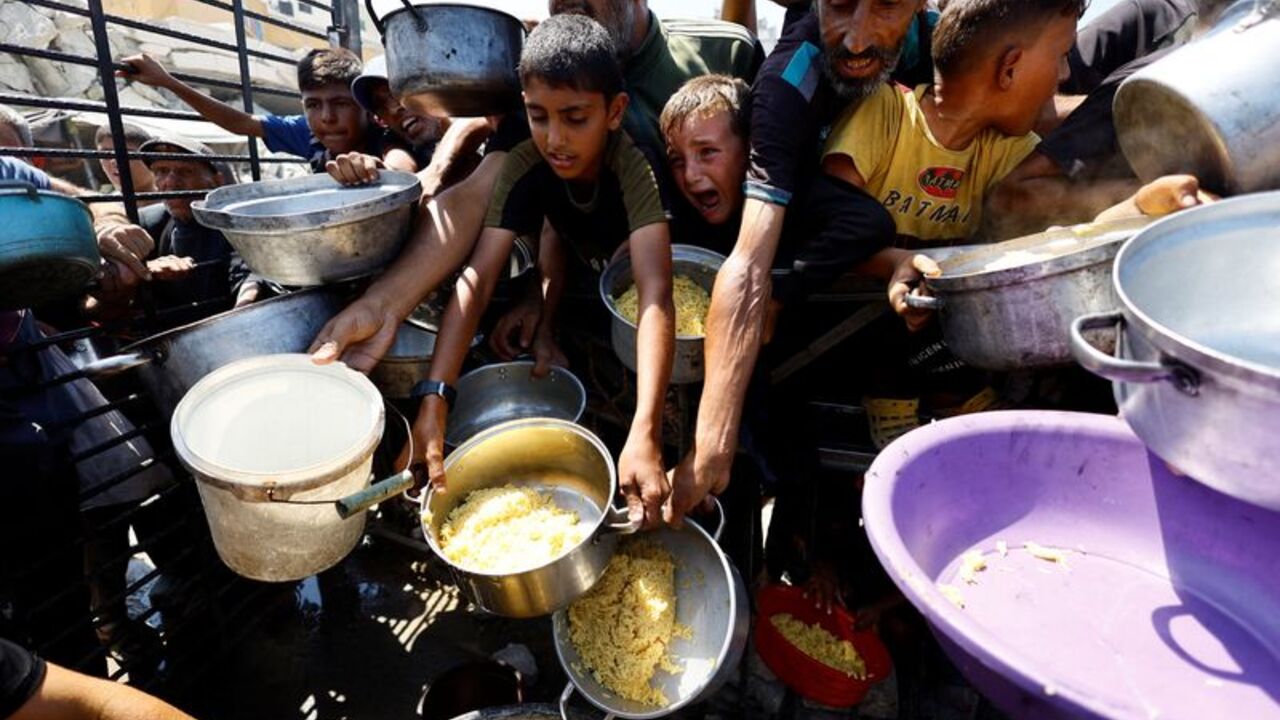Palestinians wait to receive food from a charity kitchen, in Gaza City