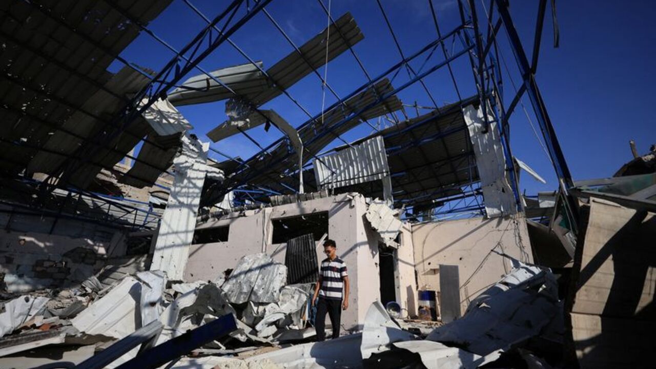 Palestinian young man stands amid the debris of Al-Hassayna family’s company warehouse, damaged during the war, in Gaza