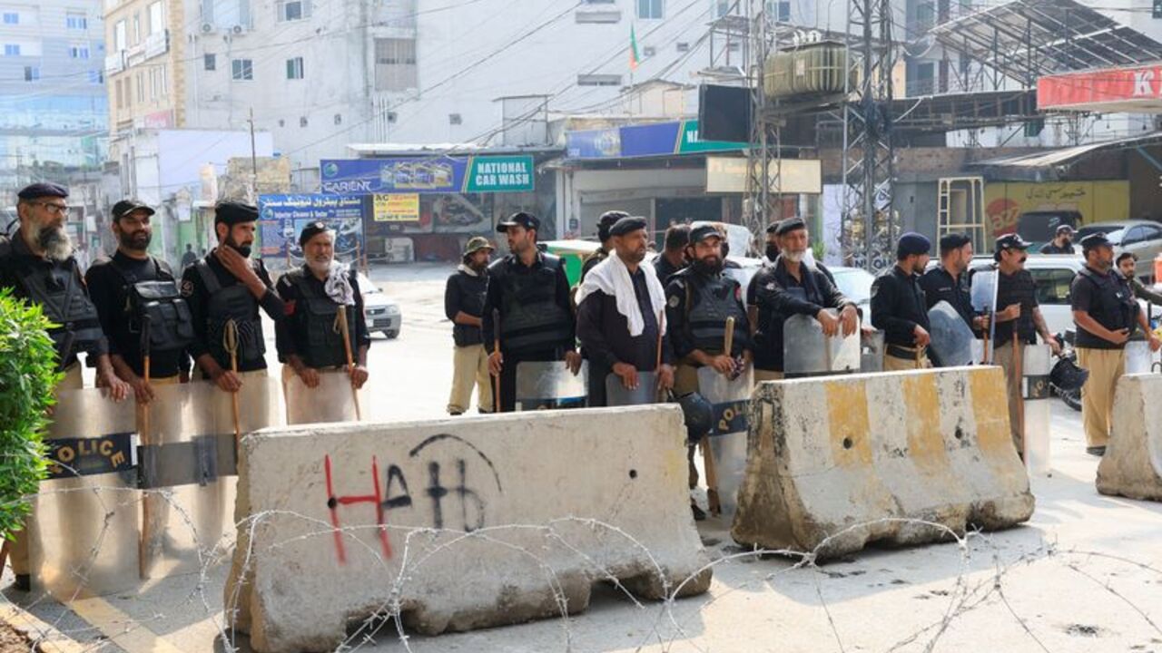 Members of the police guard a road leading to the Red Zone, in Peshawar