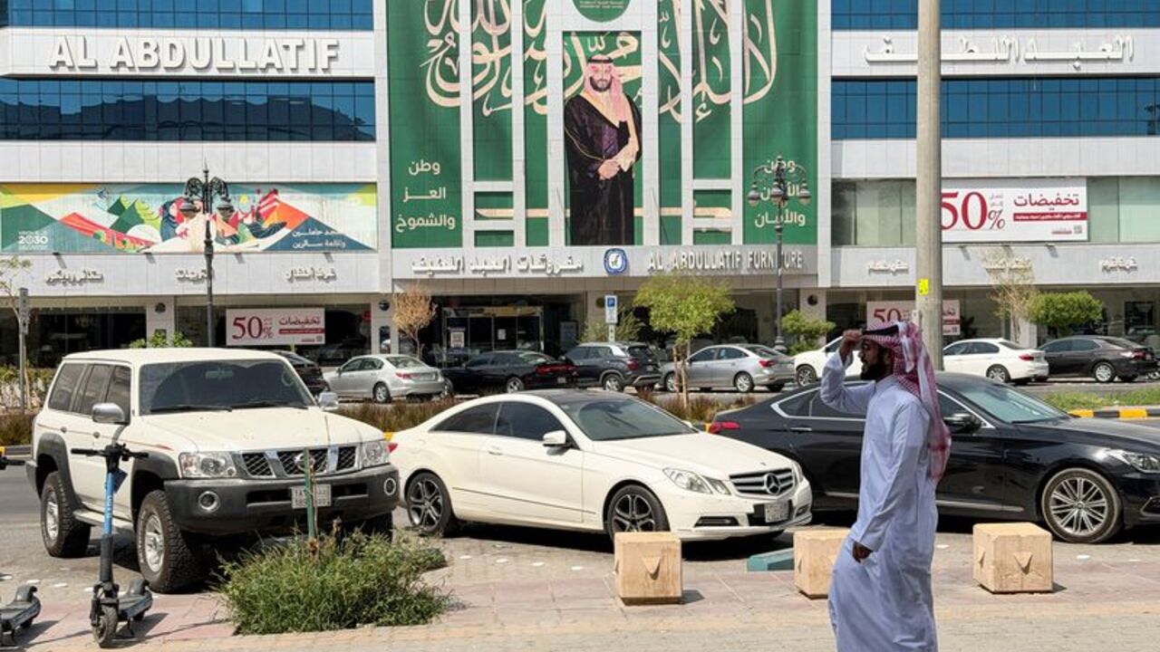 A Saudi man walks past a banner of Saudi Crown Prince Mohammed bin Salman displayed on a commercial building in Riyadh