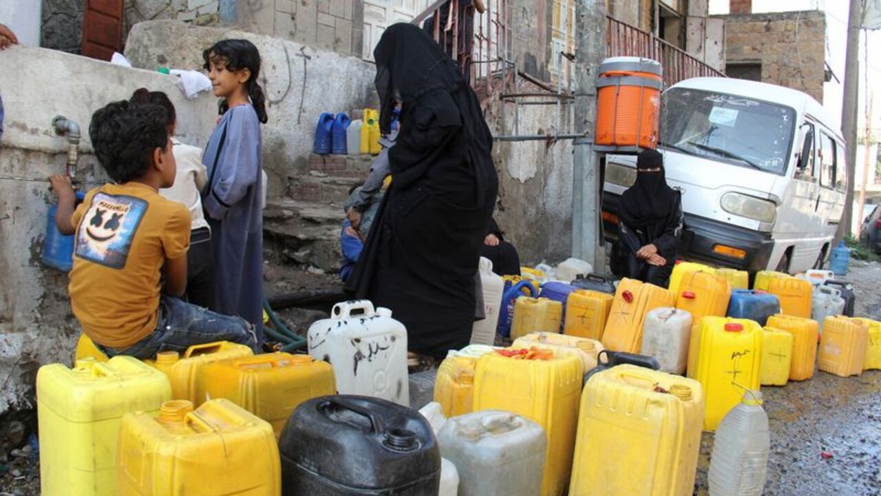 Women and children wait to fill jerrycans with drinking water from a charity tank in Taiz