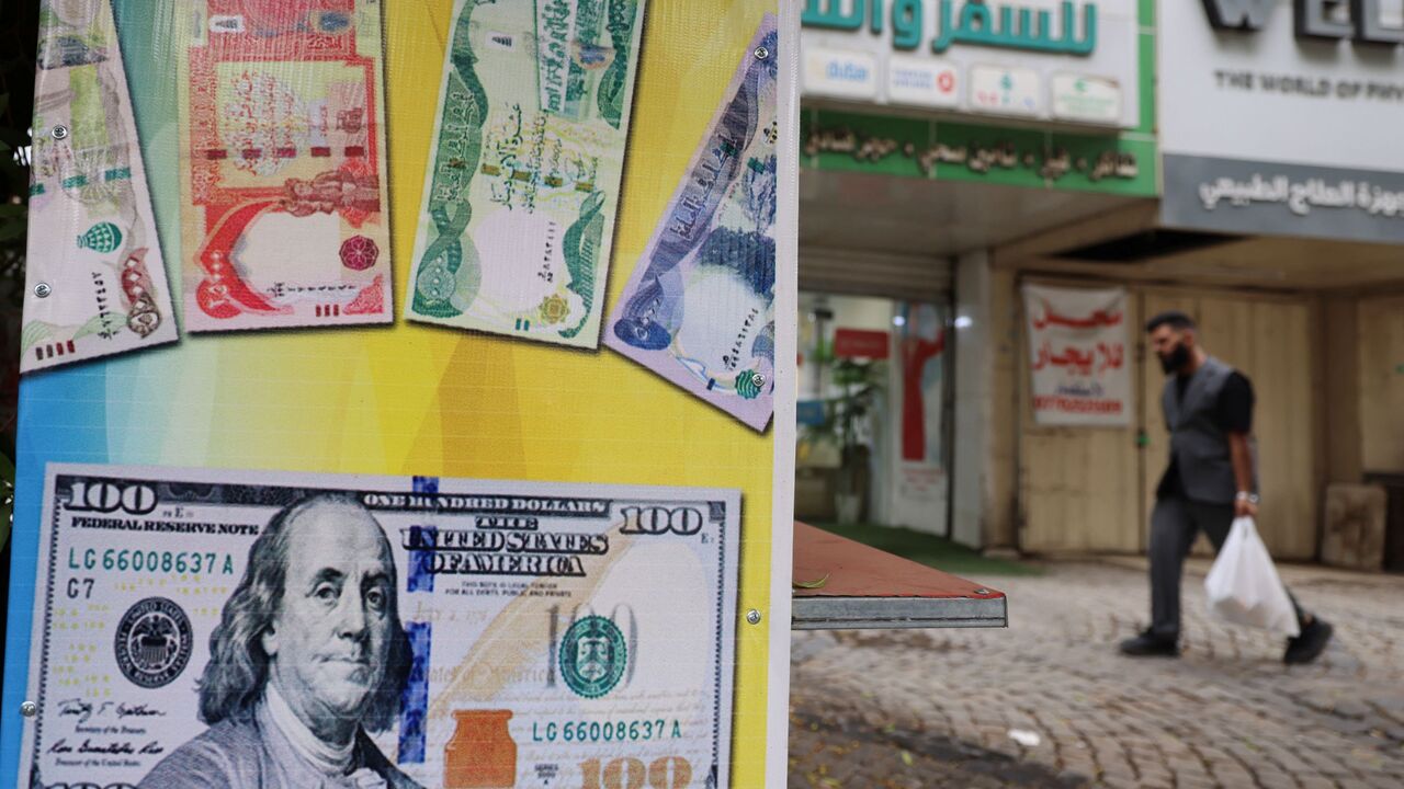 A man walks past a closed foreign exchange office in Baghdad on October 7, 2026. Iraq's central bank devalued the dinar currency against the dollar on October 7, with the country facing a deepening crisis brought on by the Middle East war. (Photo by AHMAD AL-RUBAYE / AFP via Getty Images)