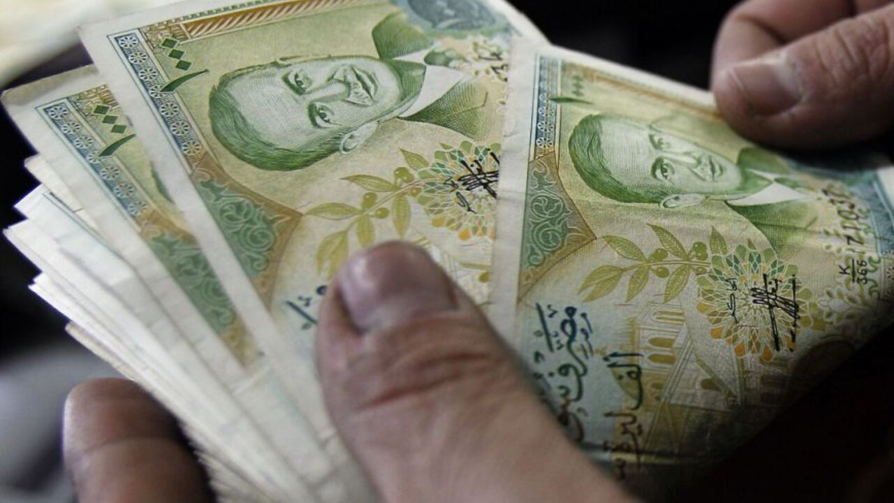 A cashier counts Syrian currency notes in Amman December 6, 2011. Jordanian money changers said on Tuesday demand on the Syrian pound has plummeted since unprecedented Arab economic sanctions against Damascus, and its exchange rate against the dollar has slipped on the black market by at least 7 percent to nearly 57 pounds.  REUTERS/Ali Jarekji  (JORDAN - Tags: BUSINESS POLITICS)