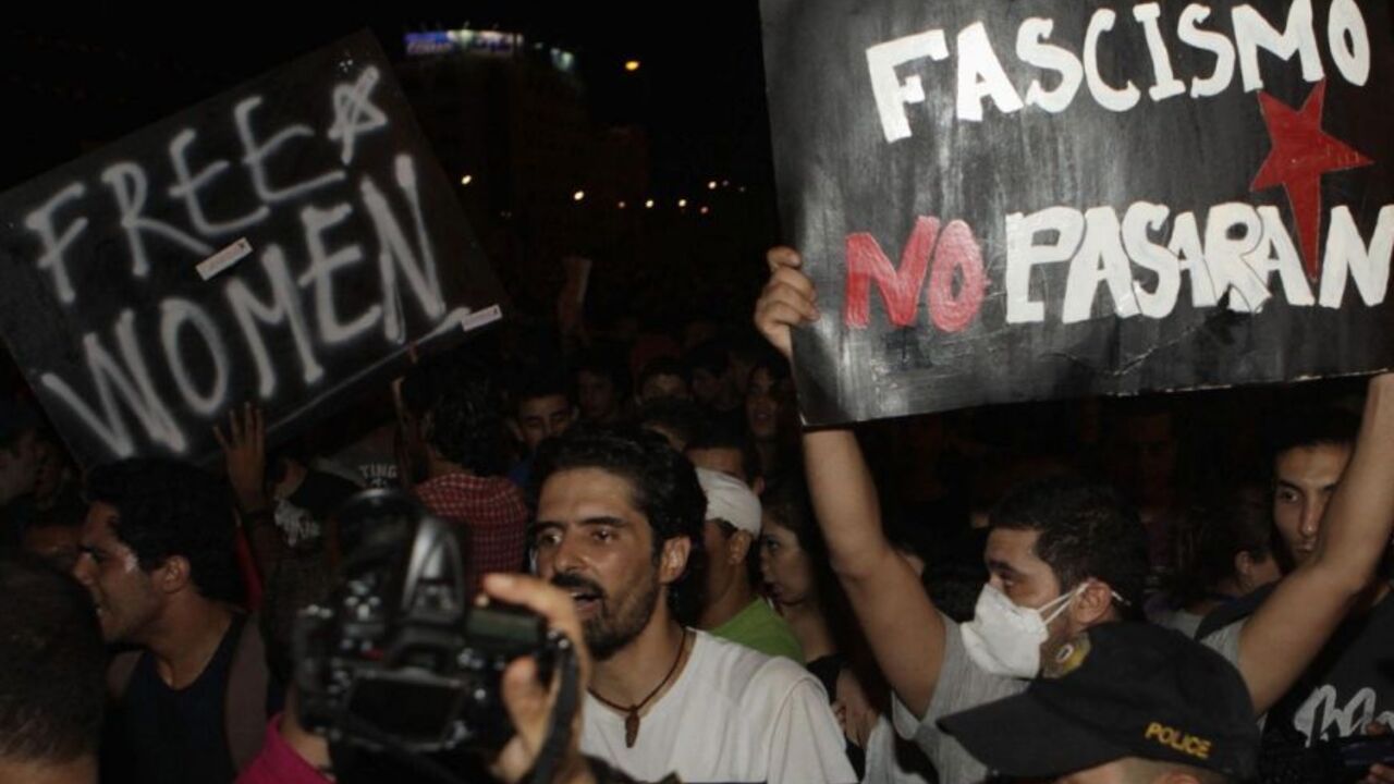 Protesters hold signs as they stand in front of riot police during a demonstration in Tunis August 13, 2012. Thousands of Tunisians rallied on Monday to protest against what they see as a push by the Islamist-led government for constitutional changes that would degrade women's status in one of the Arab world's most liberal nations. REUTERS/Zoubeir Souissi (TUNISIA - Tags: POLITICS CIVIL UNREST CRIME LAW)