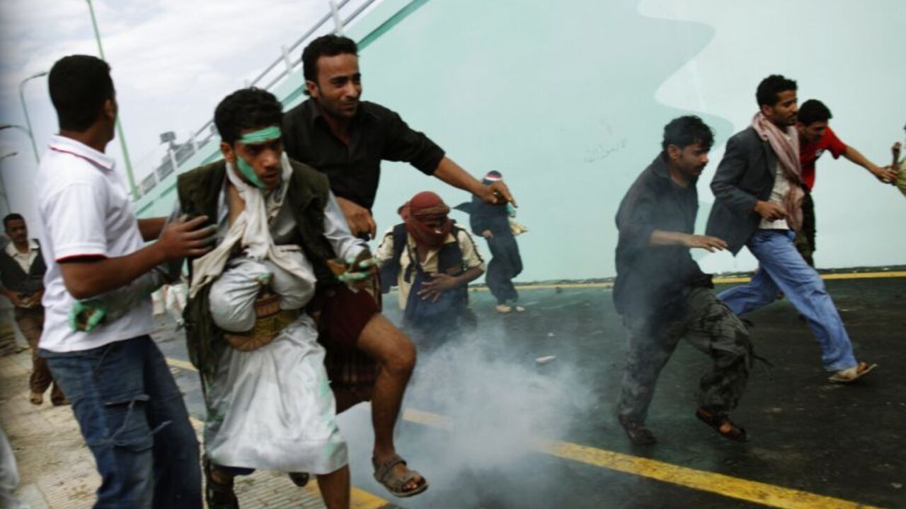 Protesters run as riot police fire tear gas at them outside the U.S. embassy in Sanaa September 13, 2012. Hundreds of Yemeni demonstrators stormed the U.S. embassy in Sanaa on Thursday in protest at a film they consider blasphemous to Islam, and clashes with security forces injured at least 15 people. REUTERS/Khaled Abdullah (YEMEN - Tags: POLITICS CIVIL UNREST RELIGION)