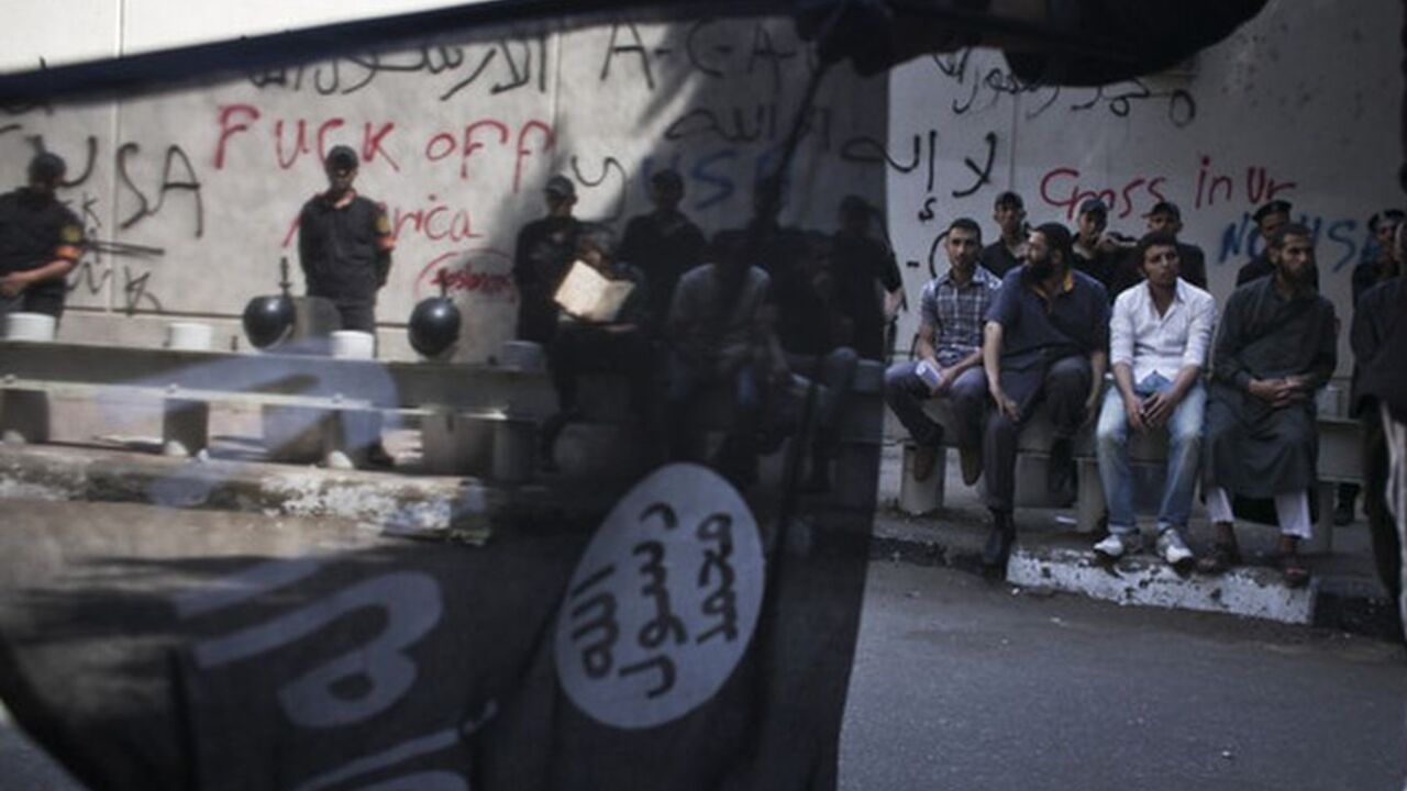 An Egyptian flag seller waves an Islamist flag in front of riot police and protesters outside of the graffitied US embassy in downtown Cairo, Egypt, Wednesday, Sept 12, 2012. (Photo by Tara Todras-Whitehill)