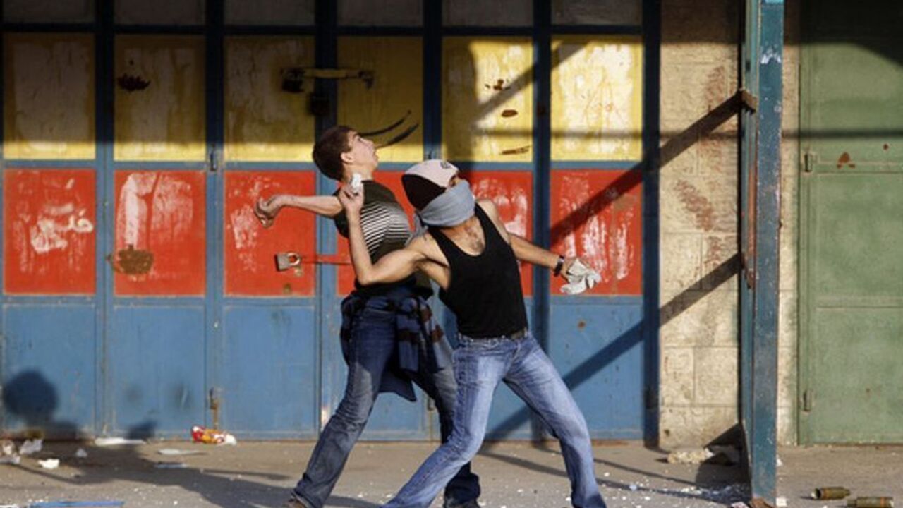 Palestinian protesters throw stones towards Israeli security forces during clashes against Israel's military operation in the Gaza Strip, at Qalandiya checkpoint near the West Bank city of Ramallah November 19, 2012. Israel bombed dozens of targets in Gaza on Monday and said that while it was prepared to step up its offensive by sending in troops, it preferred a diplomatic solution that would end Palestinian rocket fire from the enclave. REUTERS/Ammar Awad (WEST BANK - Tags: POLITICS CIVIL UNREST)