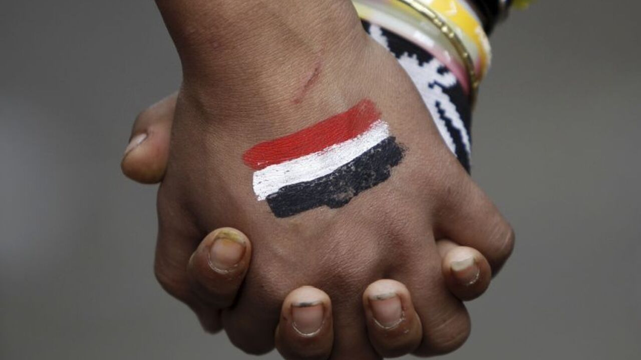 Anti-Mursi protesters, who want a peaceful demonstration, join hands as they try to stop clashes and rock-throwing at riot police along a road which leads to the U.S. embassy, near Tahrir Square in Cairo November 29, 2012. The body writing Egypt's new constitution began a session to vote on a final draft on Thursday, a move President Mohamed Mursi's allies in the Muslim Brotherhood hope will help end a crisis prompted by a decree expanding his powers. Seen on the hand is an image of the Egyptian flag. REUTE