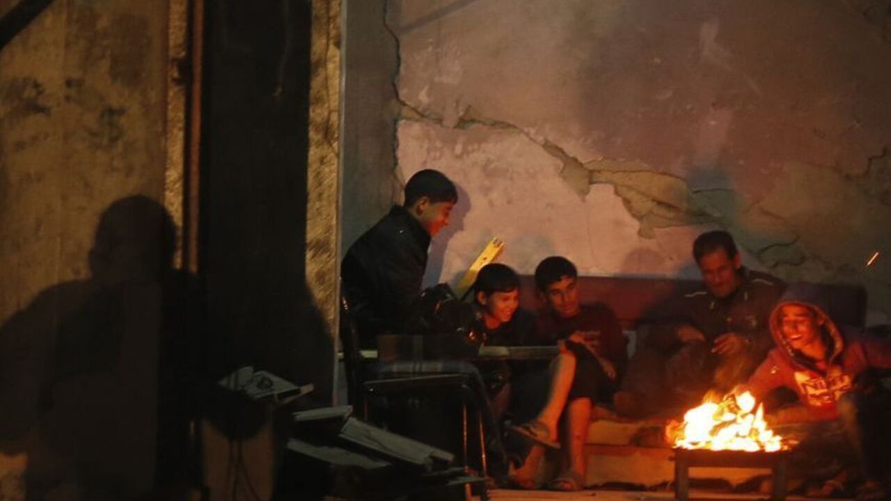Palestinians warm themselves by a fire inside a house, which witnesses said was damaged in an Israeli air strike during an eight-day conflict, in the northern Gaza Strip December 20, 2012. Eight days of Israeli air strikes on Gaza and cross-border Palestinian rocket attacks ended in an Egyptian-brokered truce agreement last month calling on Israel to ease restrictions on the territory. REUTERS/Mohammed Salem (GAZA - Tags: CONFLICT)