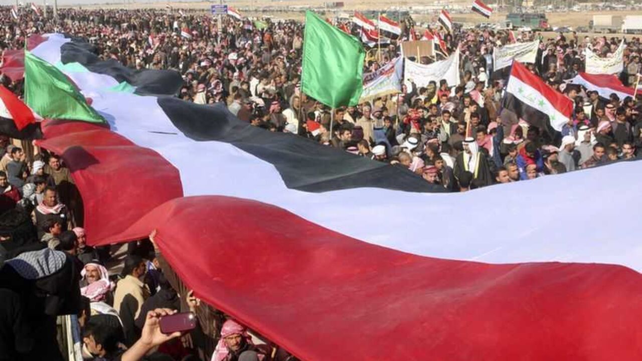 Protesters lift a giant Iraqi national flag during an anti-government demonstration in Falluja, 50 km (30 miles) west of Baghdad, January 11, 2013. Tens of thousands of Iraqi Sunni Muslims took to the streets in Baghdad and other cities after prayers on Friday, in another show of discontent with Shi'ite Prime Minister Nuri al-Maliki.    REUTERS/Mohanned Faisal (IRAQ - Tags: CIVIL UNREST POLITICS)