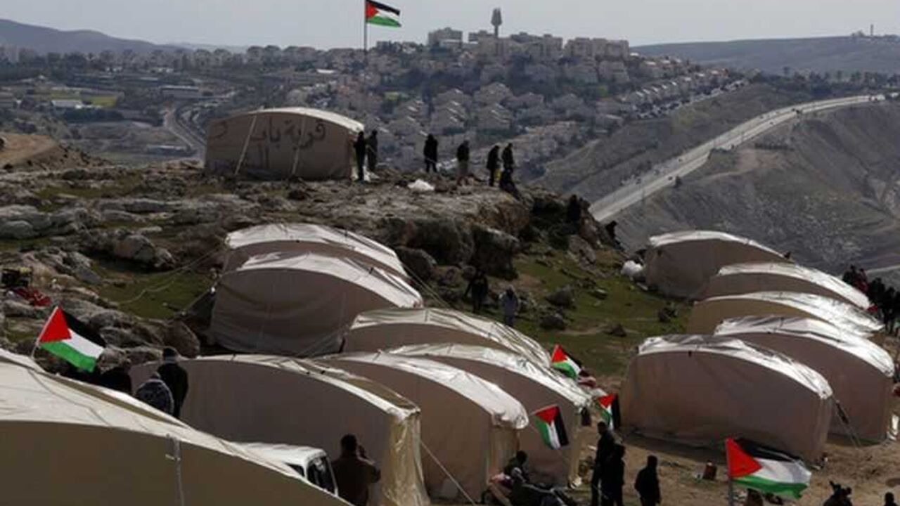Palestinians, together with Israeli and foreign activists, stand near newly-erected tents in an area known as E1, near Jerusalem January 12, 2013. Palestinians from villages in the occupied West Bank near Jerusalem pitched tents on Friday on the land Israel has earmarked for a new urban settlement, looking to preserve the area for an independent Palestinian state.  REUTER/Baz Ratner (WEST BANK - Tags: POLITICS CIVIL UNREST BUSINESS CONSTRUCTION)