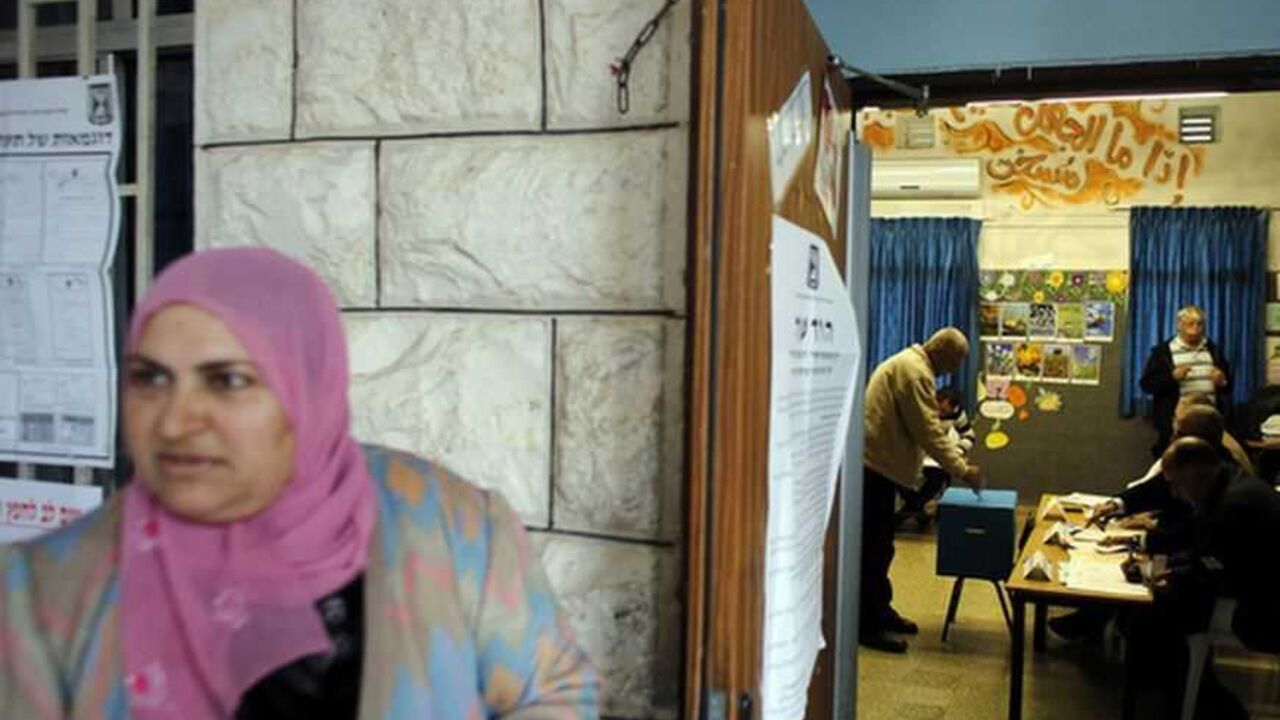 A woman waits outside as a man casts his ballot for the parliamentary election at a polling station in the northern Israeli Arab town of Sakhnin January 22, 2013. Israelis voted on Tuesday in an election that is expected to hand hawkish Prime Minister Benjamin Netanyahu a third term, opening the way for a showdown with Iran and bolstering opponents of Palestinian statehood. REUTERS/Ammar Awad (ISRAEL - Tags: POLITICS ELECTIONS)