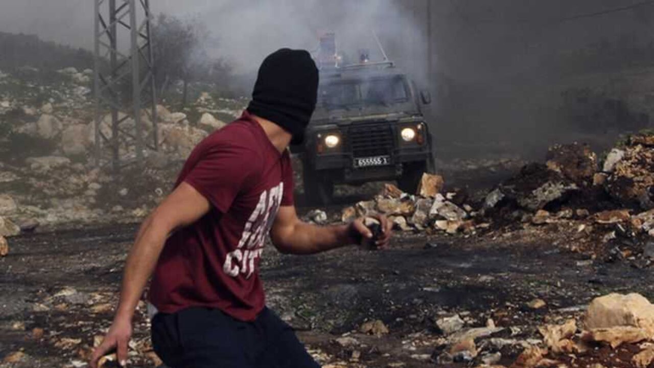 A stone-throwing Palestinian protester runs near an Israeli border police vehicle during clashes at a weekly protest against the nearby Jewish settlement of Kdumim, in the West Bank village of Kfar Kadum, near Nablus January 25, 2013. REUTERS/Abed Omar Qusini (WEST BANK - Tags: POLITICS CIVIL UNREST) - RTR3CXSG