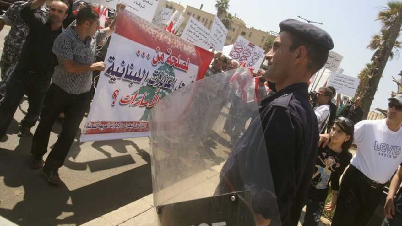 A Lebanese policeman stands guard, as Lebanese Shi'ites, who said they were forced to leave United Arab Emirates last year because of purported security reasons, hold banners during a protest to demand for their rights, in front of the UAE embassy in Beirut May 5, 2010.  REUTERS/Sharif Karim   (LEBANON - Tags: CIVIL UNREST POLITICS SOCIETY EMPLOYMENT BUSINESS) - RTR2DHH4