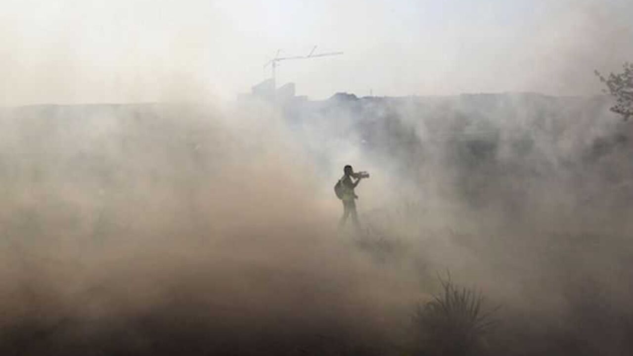 A journalist walks through tear gas fired by Israeli security officers (unseen) during clashes with stone-throwing Palestinians following a rally marking the 48th anniversary of the founding of the Fatah movement, in the West Bank village of Bilin near Ramallah January 4, 2013. REUTERS/Ammar Awad (WEST BANK - Tags: POLITICS CIVIL UNREST) - RTR3C3NU