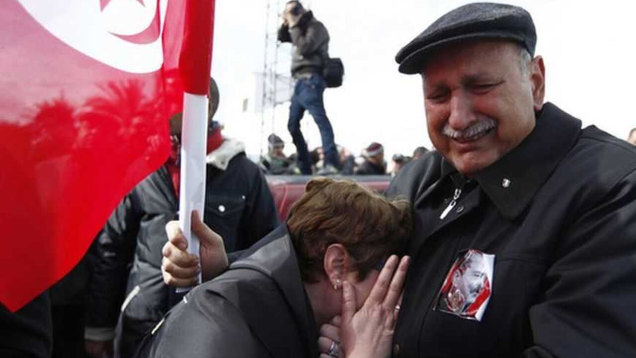 A couple mourns next to a Tunisian flag during the funeral procession for the late secular opposition leader Chokri Belaid in the Jebel Jelloud district in Tunis February 8, 2013. Tens of thousands of mourners chanted anti-Islamist slogans on Friday at the Tunis funeral of Belaid, whose assassination has plunged Tunisia deeper into political crisis. REUTERS/ Anis Mili (TUNISIA - Tags: CIVIL UNREST POLITICS OBITUARY) - RTR3DHTW
