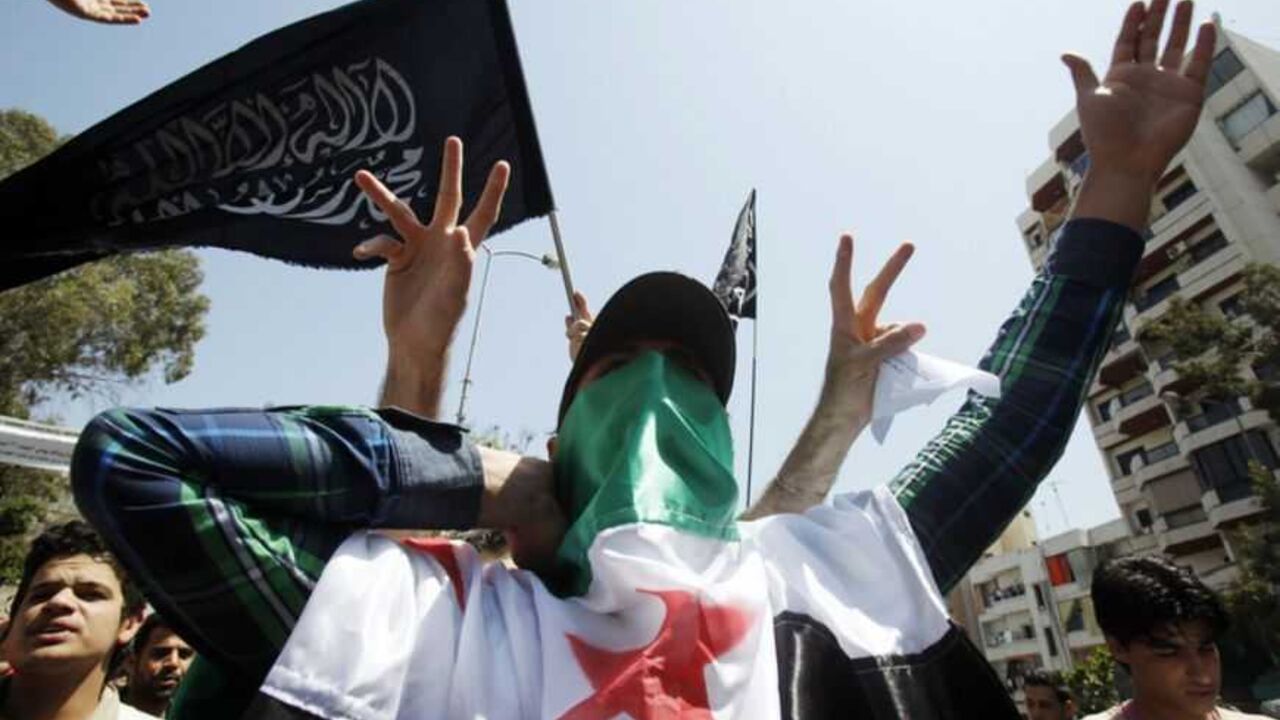 A protester covers his face with the Syrian opposition flag as he gestures and shout slogans, during a demonstration, organised by the Future Movement against Syria's President Bashar al-Assad, after Friday prayers in Beirut, April 27, 2012.   REUTERS/Sharif Karim (LEBANON - Tags: POLITICS CIVIL UNREST) - RTR31AEX