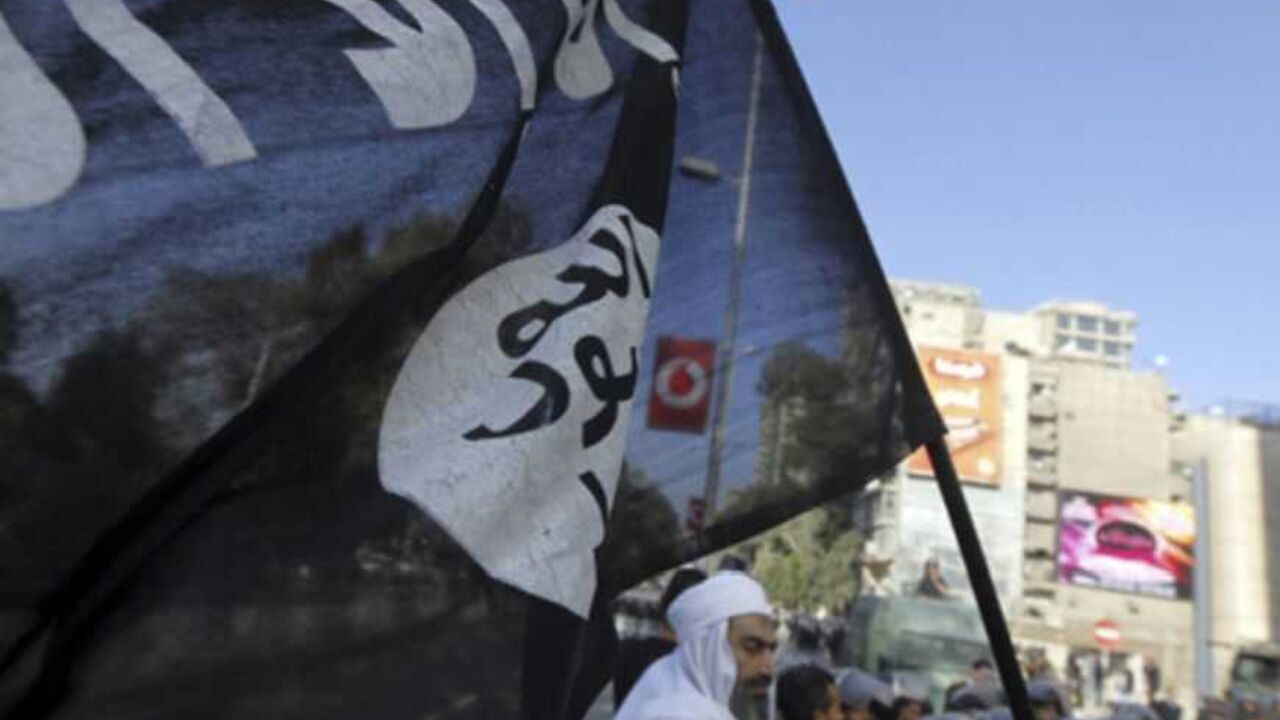 An Islamist protester holds a Salafist flag with Arabic words that read "There is no God but Allah and Mohammad is his prophet" as Egyptian security forces stand guard during a protest against the French operation in Mali outside the French embassy in Cairo January 18, 2013. REUTERS/Amr Abdallah Dalsh  (EGYPT - Tags: POLITICS CIVIL UNREST) - RTR3CLWR