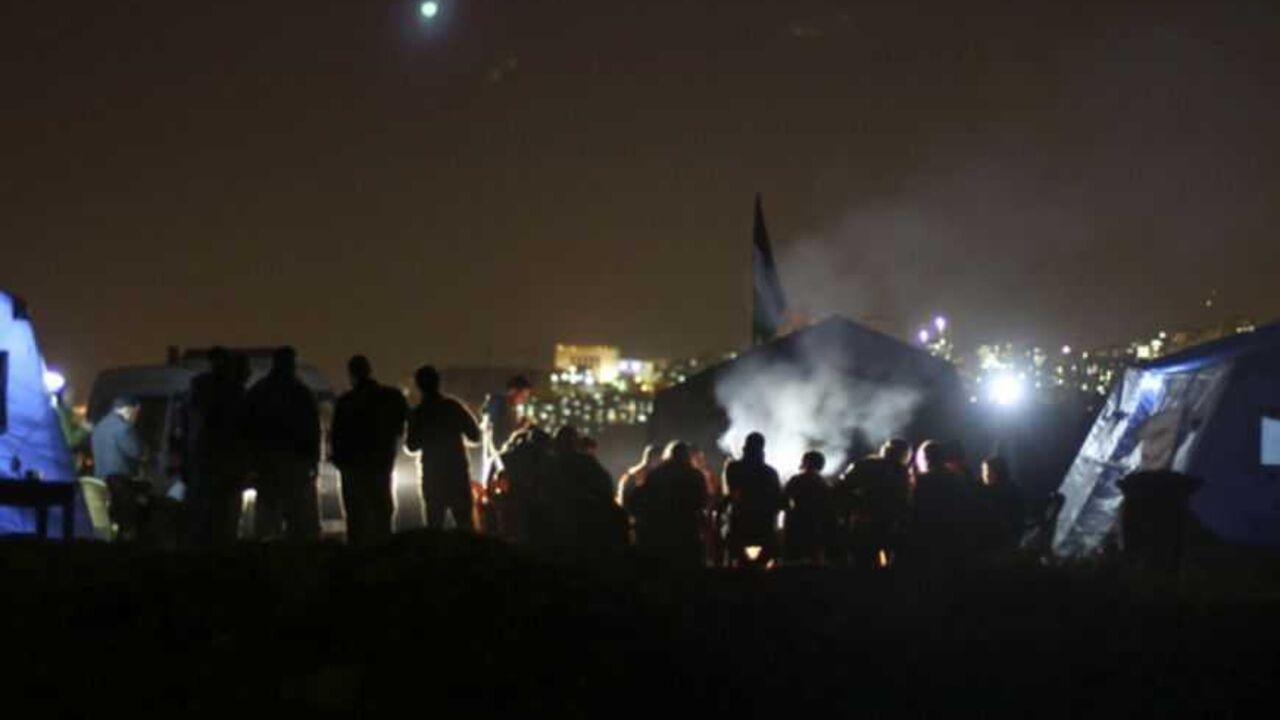 Palestinian activists stand near newly-erected tents in the West Bank village of Beit Iksa, between Ramallah and Jerusalem January 20, 2013. Palestinians pitched tents in an area of the West Bank as a protest against an Israeli barrier they said would cut villagers off from their lands. The tents were erected on Friday in the Palestinian village of Beit Iksa, north of Jerusalem. REUTERS/Mohamad Torokman (WEST BANK - Tags: POLITICS) - RTR3CPA5