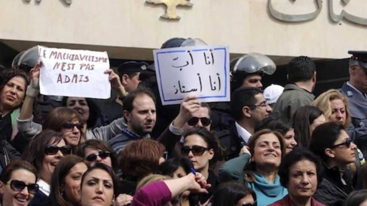 Protesters carry banners outside the Lebanese Central Bank in Beirut February 25, 2013. An open-ended strike by teachers and civil servants entered its second week today for the government to approve the wage hike proposal. The banners read " I am a father, I am a teacher" and " Machiavellism is not permited " REUTERS/Mohamed Azakir (LEBANON - Tags: POLITICS CIVIL UNREST) - RTR3E9TN