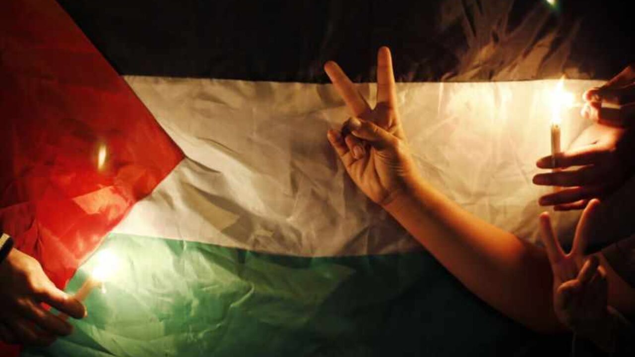 Protesters light candles in front of a Palestinian flag during a rally to show solidarity with Palestinian prisoners inside Israeli jails, in Gaza City April 15, 2013. According to a Palestinian prisoners' association, at least 4900 Palestinians remain in Israeli jails.    REUTERS/Suhaib Salem (GAZA - Tags: POLITICS CIVIL UNREST) - RTXYMTT