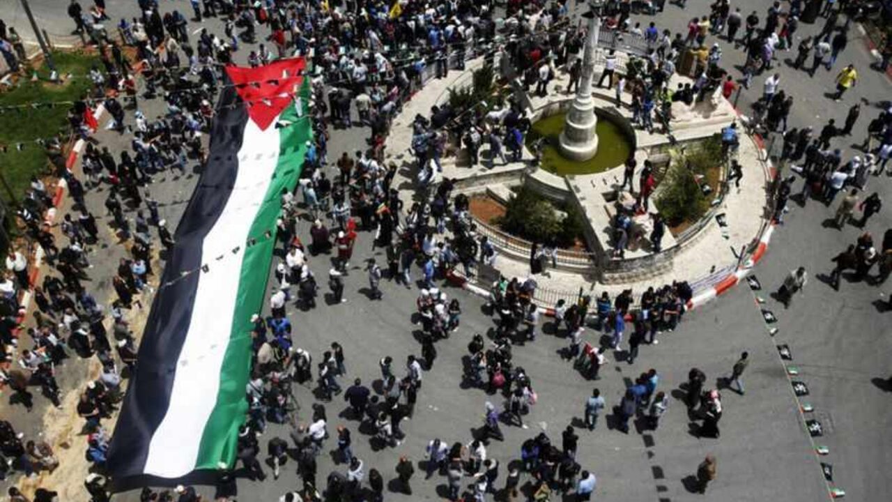 Palestinians carry a giant Palestinian flag through central Ramallah during a rally to mark Nakba Day in the West Bank city of Ramallah May 15, 2013. Palestinians clashed with Israeli forces in the occupied West Bank and at East Jerusalem on Wednesday during demonstrations to mark 65 years since what they call the Nakba (Catastrophe) when Israel's creation caused many to lose their homes and become refugees. REUTERS/Mohamad Torokman (WEST BANK - Tags: CIVIL UNREST POLITICS ANNIVERSARY) - RTXZNF8