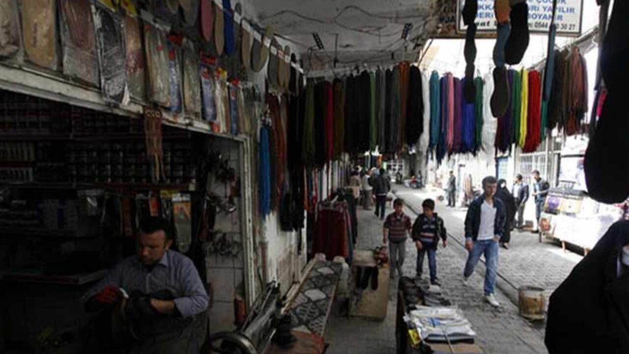 A man repairs shoes in his shop as locals pass through on a street in the town of Cizre in Sirnak province, near the border with Syria March 23, 2013. Turkey's fledgling peace process with the Kurdistan Workers Party (PKK) militant group is all over the headlines. After three decades of war, 40,000 deaths and a devastating impact on the local economy, everybody seems ready for peace. Pro-Kurdish politicians are focused on boosting minority rights and stronger local government for the Kurds, who make up abou