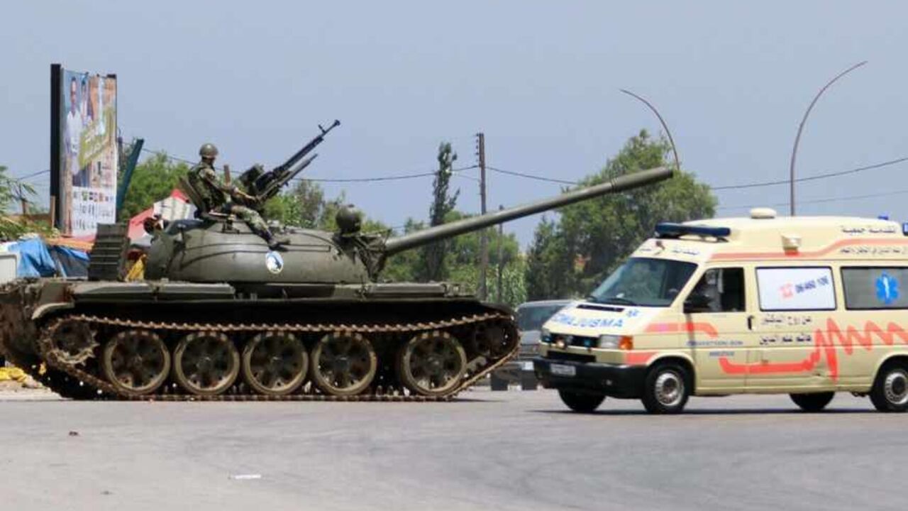 A Lebanese army soldier is seen atop his tank as an ambulance travels past in Tripoli May 20, 2013. Three people have been killed and about 40 wounded in two days of fighting in Lebanon's northern city of Tripoli, security sources said on Monday, as sectarian violence spilled over from the civil war in Syria.   REUTERS/Omar Ibrahim (LEBANON - Tags: POLITICS CIVIL UNREST MILITARY) - RTXZTWK