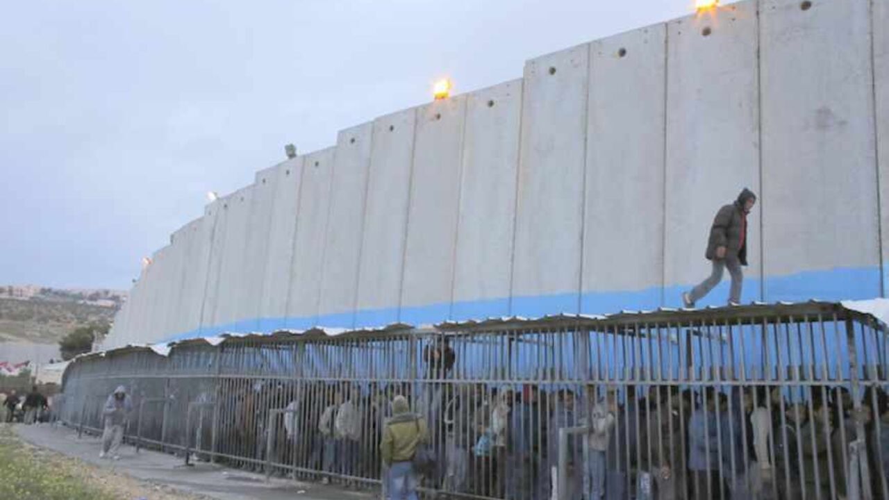 Palestinian labourers queue next to a section of the controversial Israeli barrier as they wait to cross into Jerusalem at an Israeli checkpoint in the West Bank town of Bethlehem March 18, 2013. U.S. President Barack Obama is due to make his first official visit to Israel and the Palestinian Territories this week, looking to improve ties after sometimes rocky relations with both sides during his first term in office. Israeli settlement expansion lies at the heart of much of the rancour between Israeli Prim